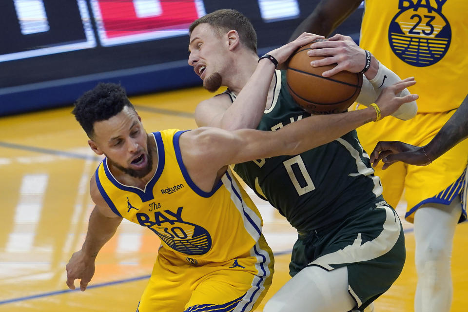 Milwaukee Bucks guard Donte DiVincenzo (0) is defended by Golden State Warriors guard Stephen Curry during the first half of an NBA basketball game in San Francisco, Tuesday, April 6, 2021. (AP Photo/Jeff Chiu)