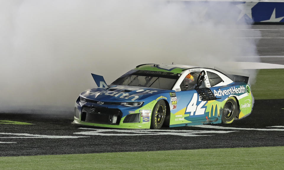 Kyle Larson holds the steering wheel out of the car as he performs a burnout after winning the NASCAR All-Star Race at Charlotte Motor Speedway in Concord, N.C., Saturday, May 18, 2019. (AP Photo/Chuck Burton)