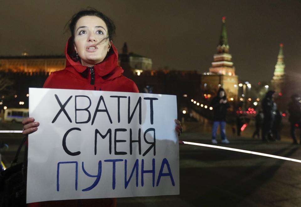 FILE - In this file photo taken on Wednesday, March 11, 2020, a protester holds a poster that reads: "Enough Putin for me", in front of the monument of the Prince Vladimir next to the Kremlin in Moscow. Putin is just a step away from bringing about the constitutional changes that would allow him to extend his rule until 2036. The vote that would reset the clock on Putin’s tenure in office and allow him to serve two more six-year terms is set to wrap up Wednesday, July 1, 2020. (AP Photo/Pavel Golovkin, File)