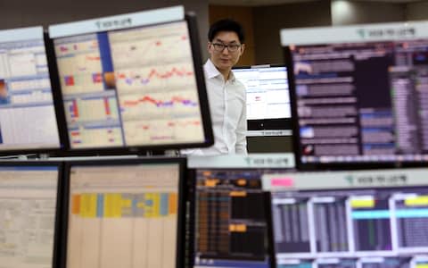 A currency trader watches monitors at the foreign exchange dealing room of the KEB Hana Bank headquarters in Seoul - Credit: AP