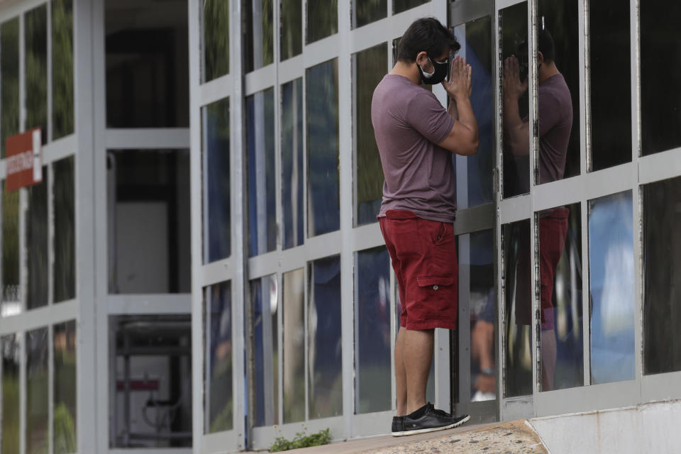 Marcio Moraes prays outside the window of an improvised ICU where his 25-year-old brother was hospitalized two days prior for COVID-19 at the public HRAN Hospital in Brasilia, Brazil, Monday, March 8, 2021. (AP Photo/Eraldo Peres)