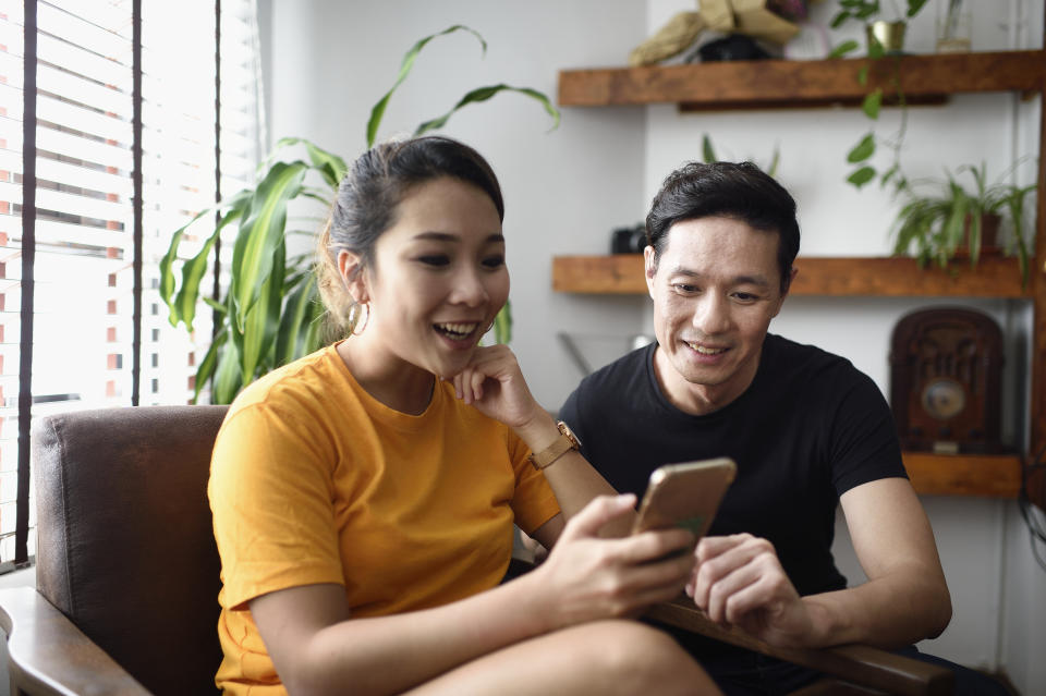 Chinese couple reading from a smart phone together at home