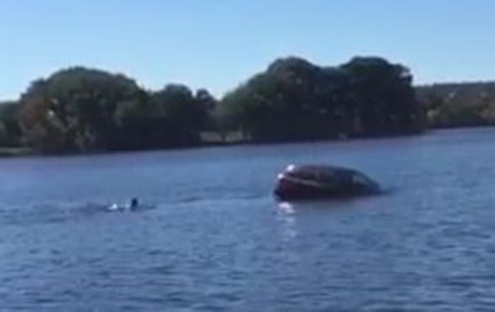 Dan Frazier starts to swin out to the car with the woman still trapped inside. Image: The Sun/John Guilfoil Public Relations