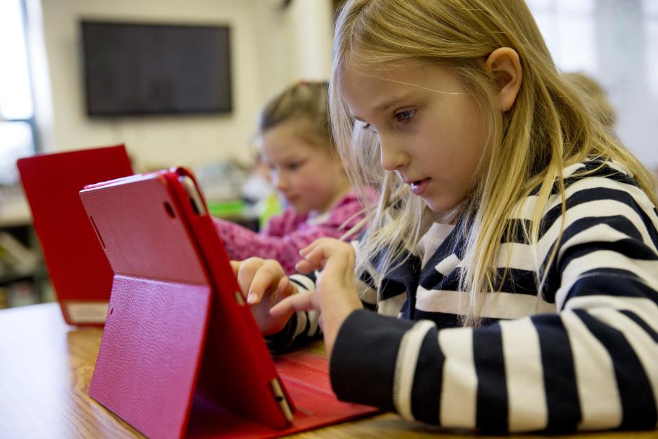 This photo taken Nov. 25, 2013 shows Ella Russell, 7, working on an e-book on an iPad during her second grade class at Jamestown Elementary School in Arlington, Va. Needed to keep a school building running these days: Water, electricity _ and broadband. Interactive digital learning on laptops and tablets is, in many cases, replacing traditional textbooks. Students are taking computer-based tests instead of fill-in-the bubble exams. Teachers are accessing far-off resources for lessons. (AP Photo/Jacquelyn Martin)