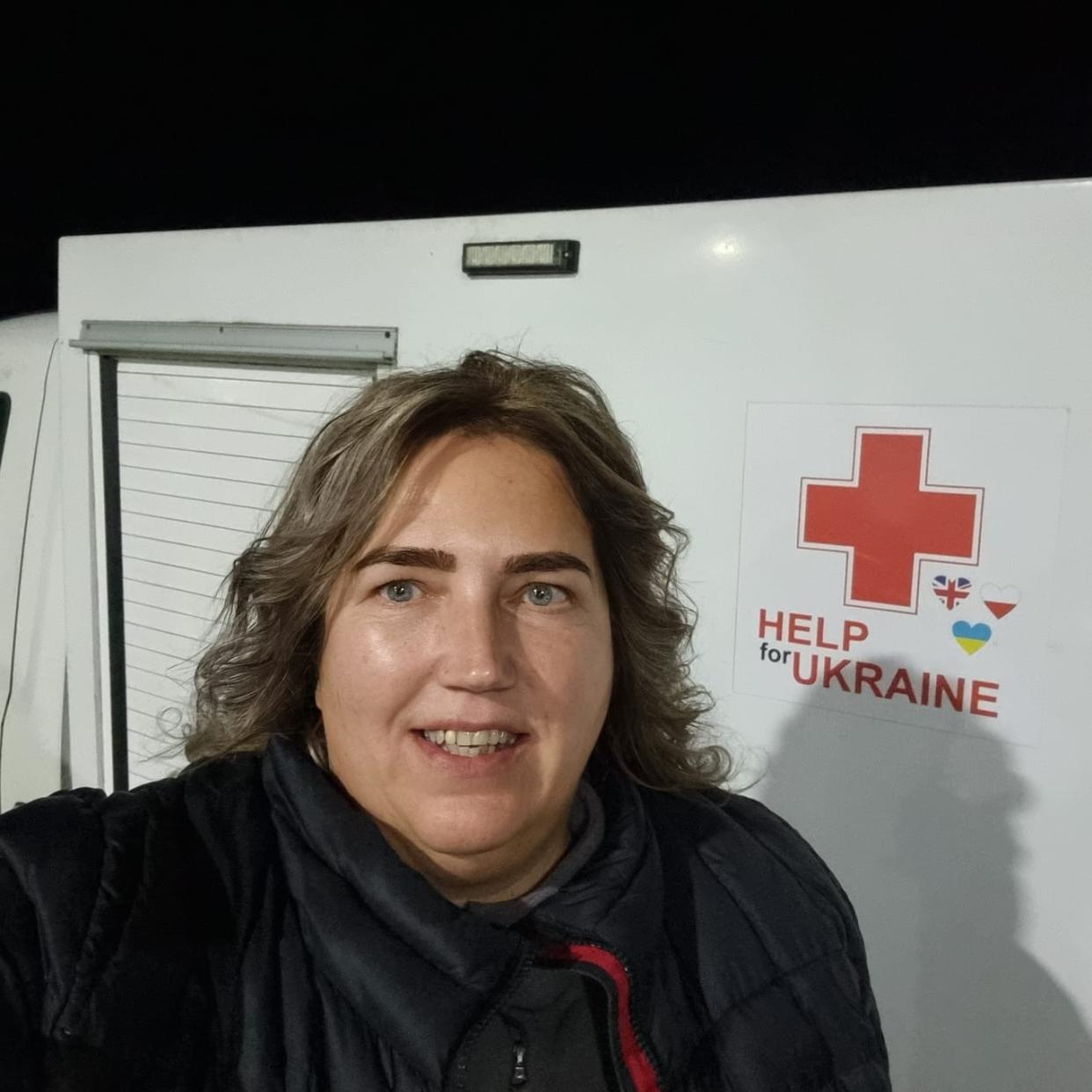 Woman smiling at the camera and standing in front of an ambulance