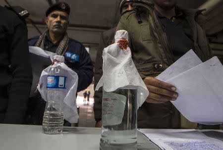 Bottles of suspected homemade alcohol are seen while police officers queue to deliver evidence to be tested at Punjab Forensic Science Agency in Lahore January 13, 2015. REUTERS/Zohra Bensemra