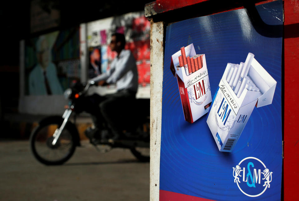 A commuter rides his bike past an advertisement for L&amp;M cigarettes, a Philip Morris International brand, at a kiosk along a road in Karachi, Pakistan in May 2018. (Photo: Akhtar Soomro / Reuters)