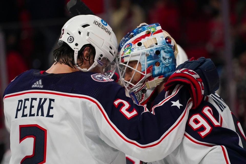 Jan 13, 2022; Raleigh, North Carolina, USA;  Columbus Blue Jackets goaltender Elvis Merzlikins (90) and  defenseman Andrew Peeke (2) celebrate the win against the Carolina Hurricanes at PNC Arena. Mandatory Credit: James Guillory-USA TODAY Sports