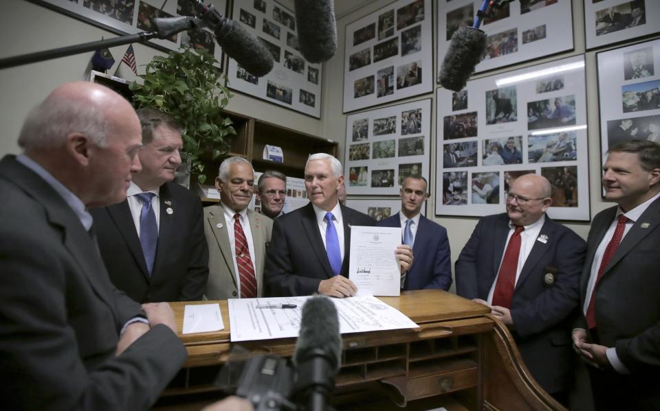 FILE - In this Thursday, Nov. 7, 2019, file photo, Republican Vice President Mike Pence, center, speaks to Secretary of State Bill Gardner, left, as Pence files for President Donald Trump to be listed on the New Hampshire primary ballot in Concord, N.H. At right is New Hampshire Gov. Chris Sununu. The quadrennial chaos has quieted down over at the New Hampshire secretary of state’s office with the closing of the filing period for the first-in-the-nation presidential primary. (AP Photo/Charles Krupa, File)