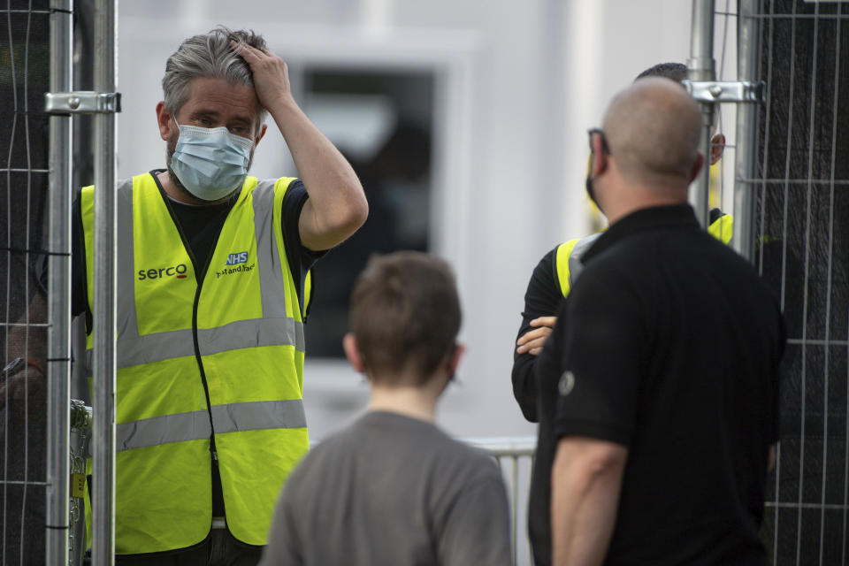 A man speaks with staff at the entrance to a coronavirus testing facility in Sutton Coldfield, England, Tuesday Sept. 13, 2020. New measures are in place banning people from different homes from meeting together in some English cities, in response to a local rocketing coronavirus infection rate, although there is widespread criticism over the availability of testing facilities. (Jacob King/PA via AP)