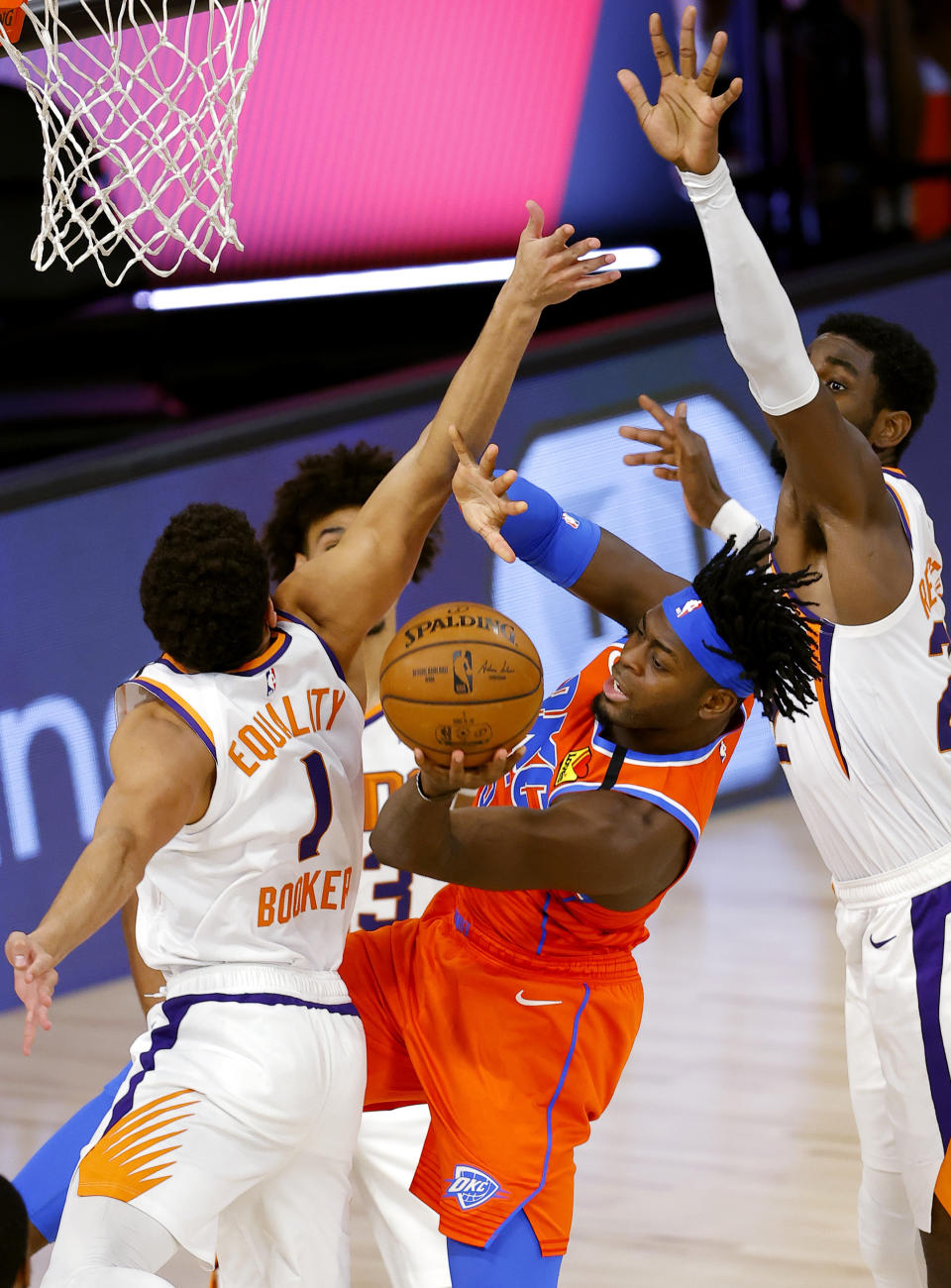 Oklahoma City Thunder's Luguentz Dort, center, passes around Phoenix Suns' Devin Booker (1) and Deandre Ayton (22) during the third quarter of an NBA basketball game Monday, Aug. 10, 2020, in Lake Buena Vista, Fla. (Mike Ehrmann/Pool Photo via AP)