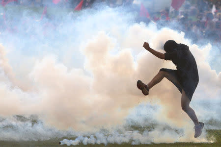 An anti-government demonstrator kicks back a tear gas canister during a clash with riot policemen during a protest against a constitutional amendment, known as PEC 55, that limits public spending, in front of Brazil's National Congress in Brasilia, Brazil November 29, 2016. REUTERS/Adriano Machado