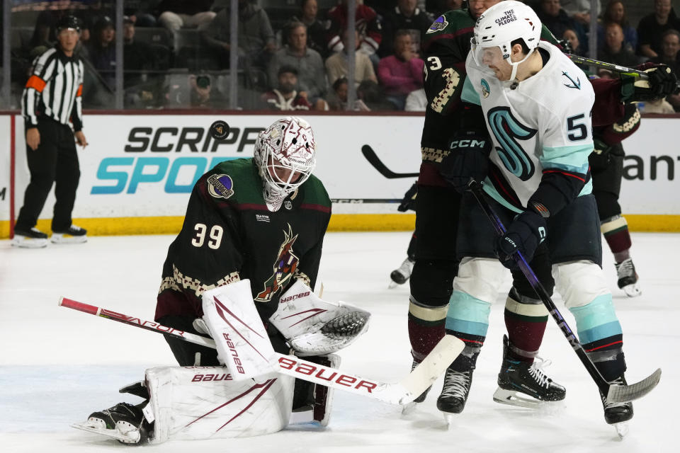 Arizona Coyotes goaltender Connor Ingram (39) makes a save on a deflection from Seattle Kraken left wing Tye Kartye, right, during the second period of an NHL hockey game Tuesday, Nov. 7, 2023, in Tempe, Ariz. (AP Photo/Ross D. Franklin)