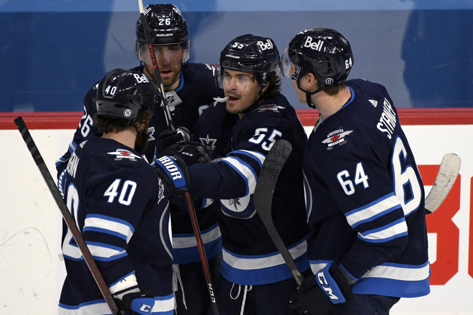 Winnipeg Jets' Mark Scheifele (55) celebrates his goal against the Vancouver Canucks with Jordie Benn (40), Blake Wheeler (26) and Logan Stanley (64) during the second period of an NHL hockey game Tuesday, May 11, 2021, in Winnipeg, Manitoba. (Fred Greenslade/The Canadian Press via AP)