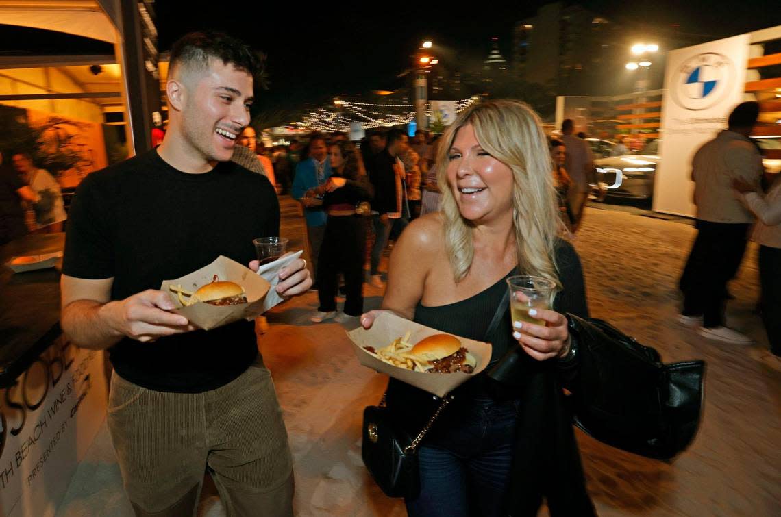 Justin Mantrana and Nelly Lamberty walk off with a couple of burgers during the Heinz Burger Bash at the South Beach Wine & Food Festival on Miami Beach, Florida on Thursday, February 22, 2024.