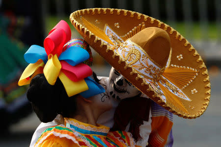 A couple dressed up as a "Catrina and Catrin", a Mexican character also known as "The Elegant Death", kisses as they participate in a procession to commemorate Day of the Dead in Mexico City, Mexico, October 28, 2017. REUTERS/Edgard Garrido