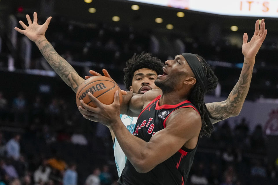 Toronto Raptors forward Precious Achiuwa drives to the basket past Charlotte Hornets center Nick Richards during the first half of an NBA basketball game Friday, Dec. 8, 2023, in Charlotte, N.C. (AP Photo/Chris Carlson)