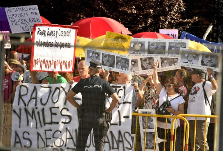 People hold banners saying 'Rajoy is robbing the poor'