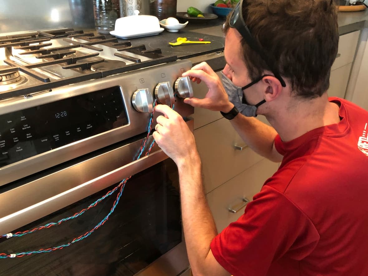 In this photo provided by climate scientist Rob Jackson, researcher Eric Lebel attaches sensors to a stove to measure how often it is used in Stanford, Calif., in 2020. According to a study published Thursday, Jan. 27, 2022, in the journal Environmental Science & Technology, gas stoves are worse for the climate than previously thought because of constant tiny methane leaks even while they're off. (Rob Jackson/The Associated Press - image credit)