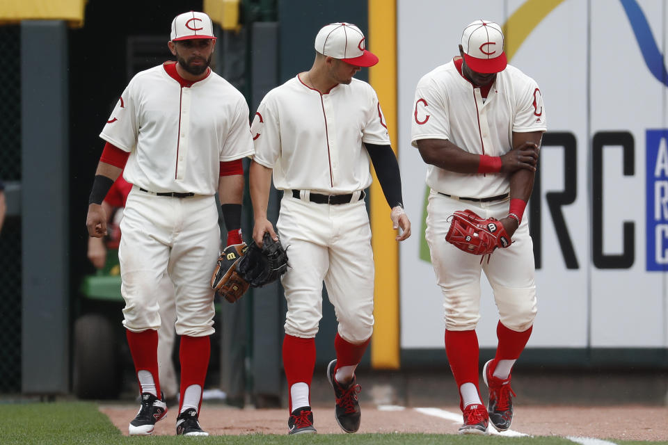 Cincinnati Reds right fielder Yasiel Puig, right, holds his arm alongside center fielder Nick Senzel, center, and left fielder Jose Peraza, left, after colliding with the outfield wall on a play in the sixth inning of a baseball game against the Los Angeles Dodgers, Sunday, May 19, 2019, in Cincinnati. (AP Photo/John Minchillo)