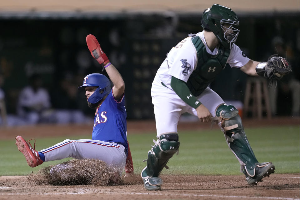 Texas Rangers' Jonathan Ornelas, left, scores next to Oakland Athletics catcher Shea Langeliers during the eighth inning of a baseball game in Oakland, Calif., Monday, Aug. 7, 2023. (AP Photo/Jeff Chiu)