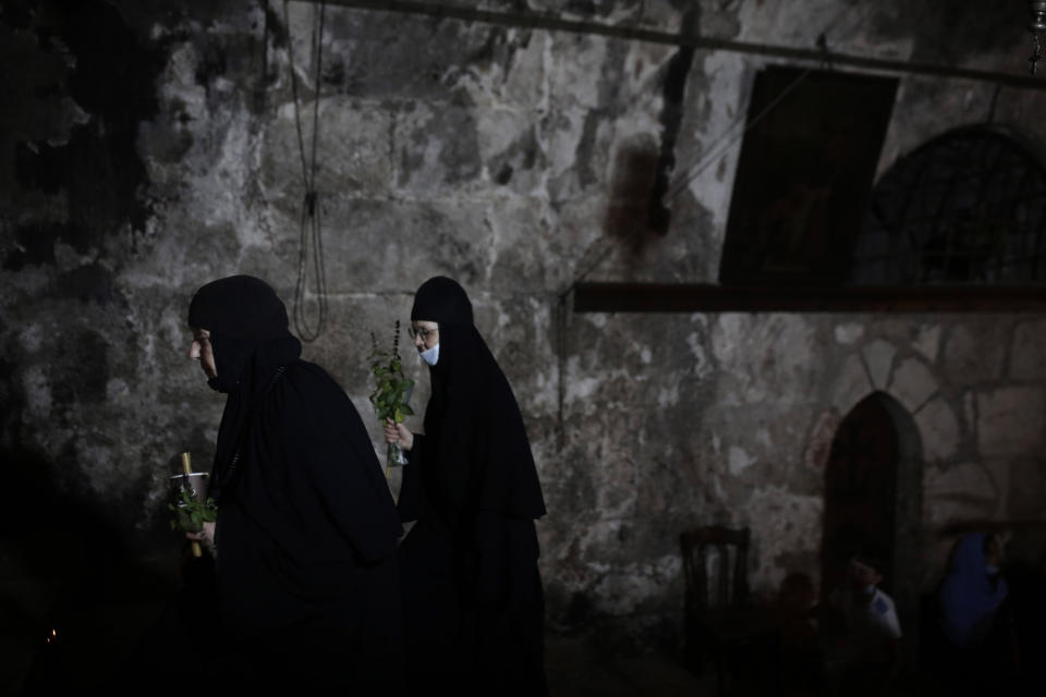 Orthodox nuns carry herbs and flowers after visiting the tomb where the Virgin Mary is believed to be buried, just outside the walls of Jerusalem's Old City, at the end of a procession in which her icon was brought from the Church of the Holy Sepulchre, early Tuesday, Aug. 25, 2020. (AP Photo/Maya Alleruzzo)