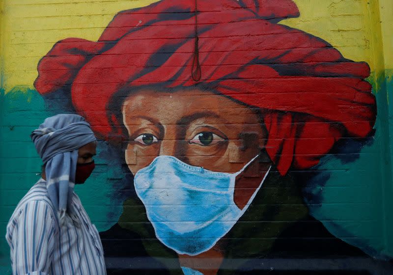 A man walks past a mural on a street, amidst the spread of COVID-19, in Mumbai