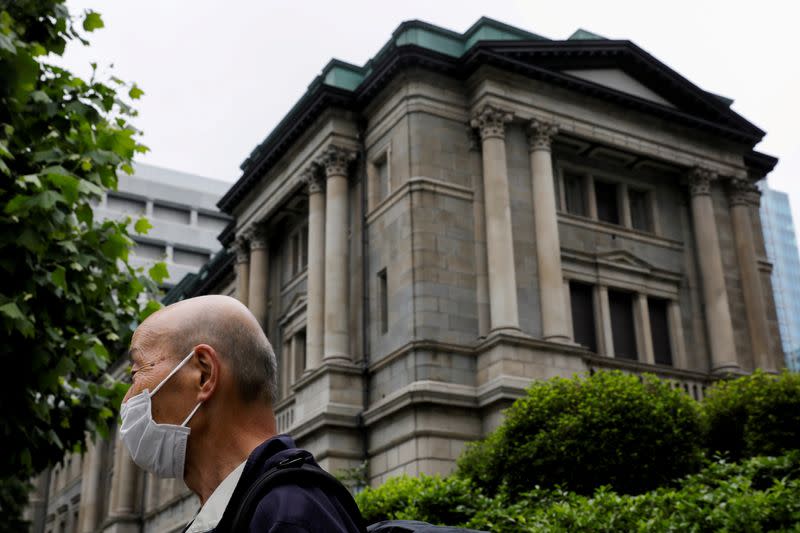 FILE PHOTO: A man wearing a protective mask stands in front of the headquarters of the Bank of Japan in Tokyo