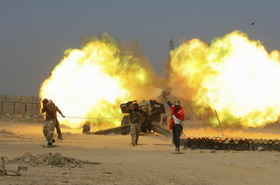 FILE - In this May 29, 2016 file photo, Iraqi security forces and allied Popular Mobilization forces fire artillery during fight against Islamic State militants in Fallujah, Iraq. When U.S. Secretary of State Mike Pompeo sat down with Iraqi officials in Baghdad earlier this month as tensions were mounting between the U.S. and Iran, he delivered a nuanced message: If you're not going to stand with us, stand aside. (AP Photo/Anmar Khalil, File)