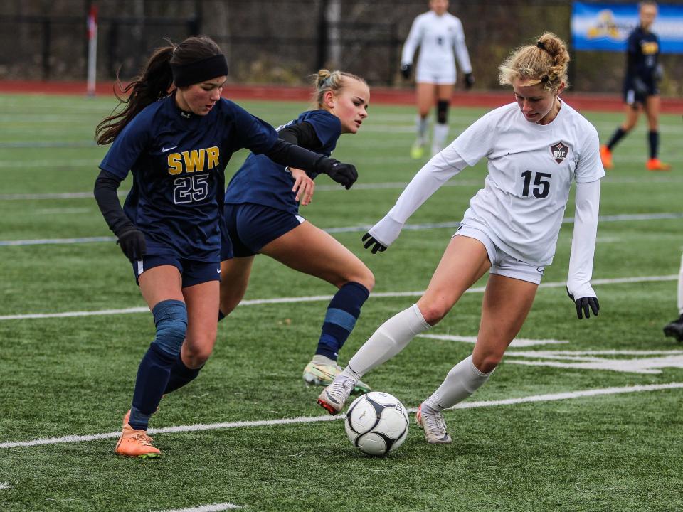 Rye's Charlotte Keenan tries to dribble away from a couple of Shoreham-Wading River defenders during the NYSPHSAA Class A girls soccer state championship match at Cortland High School on Sunday, Nov. 12, 2023.