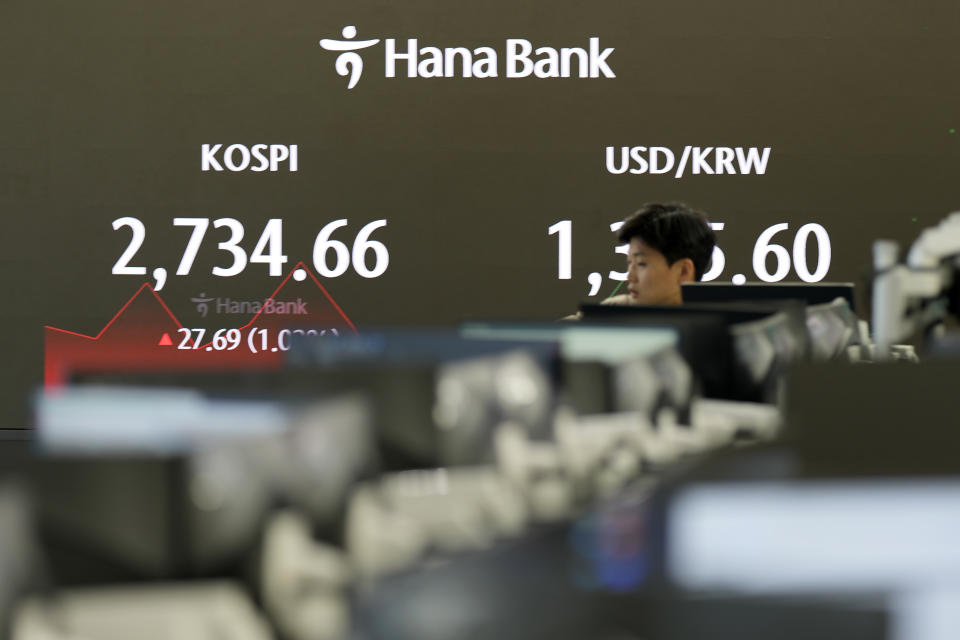 A currency trader walks by the screens showing the Korea Composite Stock Price Index (KOSPI), left, and the foreign exchange rate between the U.S. dollar and South Korean won at a foreign exchange dealing room in Seoul, South Korea, Thursday, April 4, 2024. Asian shares mostly rose Thursday after a firm finish on Wall Street, as expectations remained solid for U.S. interest rate cuts this year. (AP Photo/Lee Jin-man)