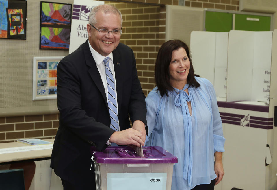 Australian Prime Minister Scott Morrison, left, is assisted by his wife, Jenny, as he casts his ballot in a federal election in Sydney, Australia, Saturday, May 18, 2019. Political leaders continued frenetic 11th-hour campaigning as Australians vote on Saturday in an election likely to deliver the nation's sixth prime minister in as many years. (AP Photo/Rick Rycroft)