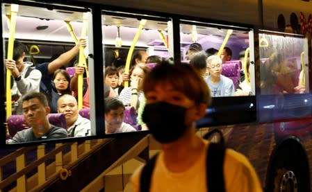 People look out from a bus as protesters walk amongst the traffic on the highway away from Hong Kong International Airport, in Hong Kong