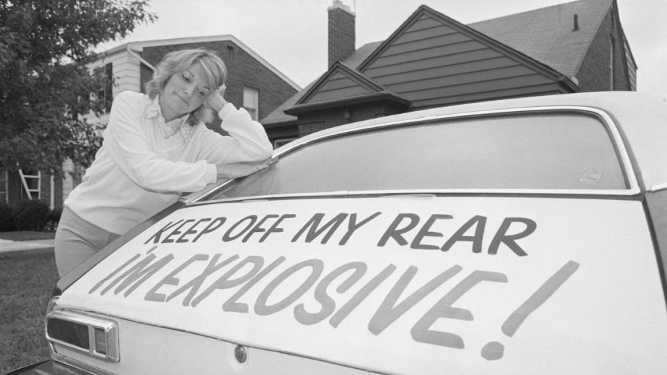 Woman Leaning on Ford Pinto with Warning Sign