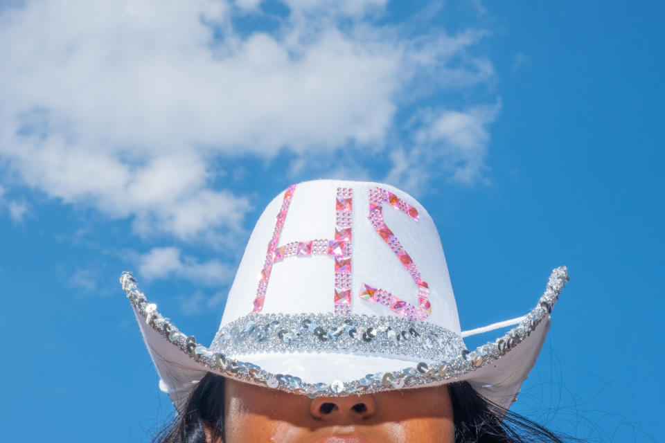 a bedazzled white cowboy hat that reads "HS" in pink letters