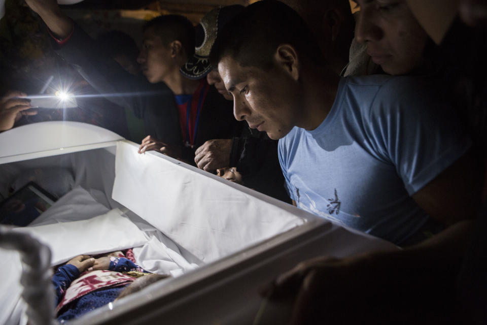 Family members pay their final respects to 7-year-old Jakelin Caal Maquin during a memorial service in her grandparent's home in San Antonio Secortez, Guatemala, Monday, Dec. 24, 2018. The body of the 7-year-old girl who died while in the custody of the U.S. Border Patrol was handed over to family members in her native Guatemala on Monday for a last goodbye. (AP Photo/ Oliver de Ros)
