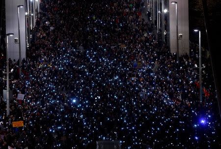 Tens of thousands of Hungarians hold up their mobile phones as they march across the Elisabeth Bridge during a protest against new tax on Internet data transfers in centre of Budapest, October 28, 2014. REUTERS/Laszlo Balogh