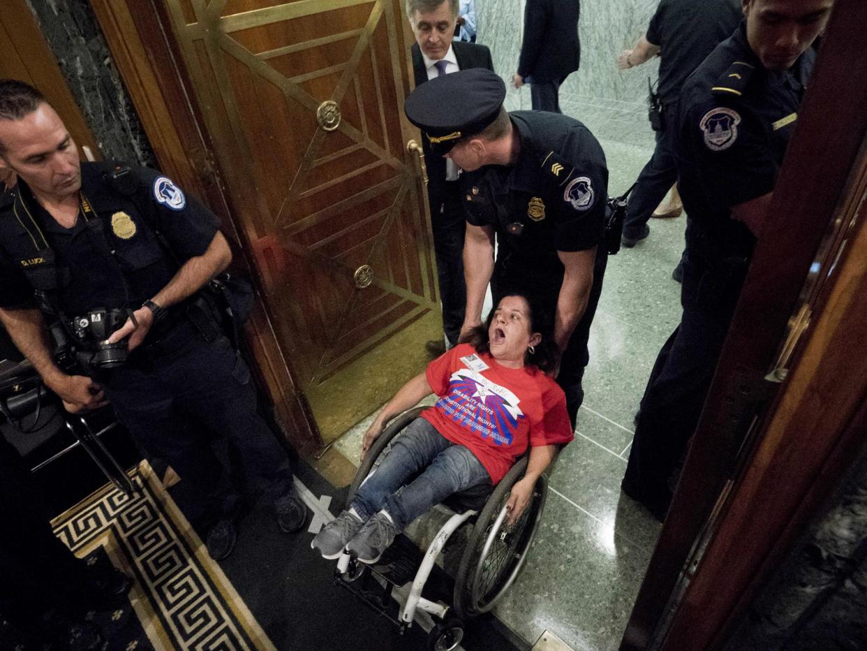 A woman in a wheelchair is removed after disrupting a Senate Finance Committee hearing to consider the Graham-Cassidy healthcare proposal on Capitol Hill on 25 September: AP Photo/Andrew Harnik