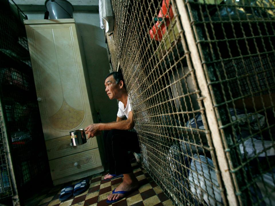 In 2009, Kong Siu-kau, 63, a cage home resident for several years relying on government pension, sits in his cage bed in Hong Kong March 20, 2009.