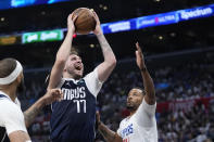 FILE - Dallas Mavericks guard Luka Doncic, center, shoots as Los Angeles Clippers guard Norman Powell, right, defends during the second half in Game 5 of an NBA basketball first-round playoff series Wednesday, May 1, 2024, in Los Angeles. Doncic, Nikola Jokic and Shai Gilgeous-Alexander are the three finalists for the NBA MVP Award that will be announced Wednesday, May 8, 2024. (AP Photo/Mark J. Terrill, File)