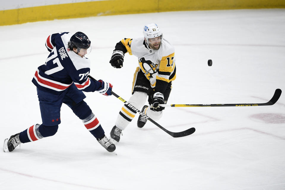 Washington Capitals right wing T.J. Oshie (77) shoots the puck next to Pittsburgh Penguins right wing Bryan Rust (17) during the second period of an NHL hockey game, Saturday, May 1, 2021, in Washington. (AP Photo/Nick Wass)