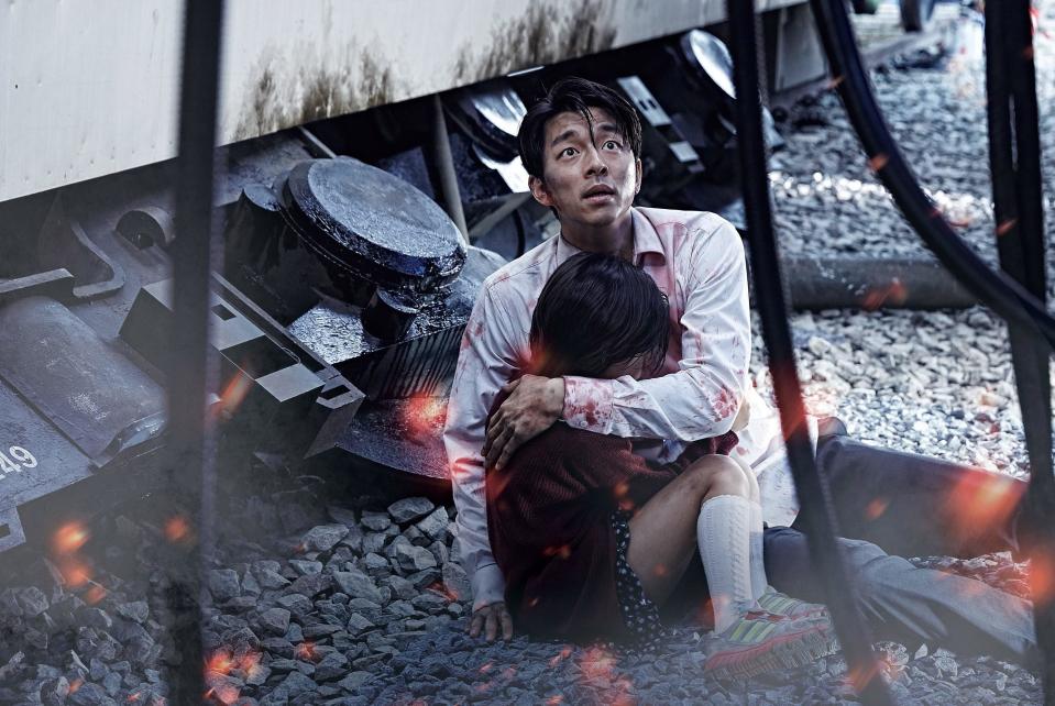 Gong Yoo embraces Soo-An Kim while staring at a terrifying threat on a train