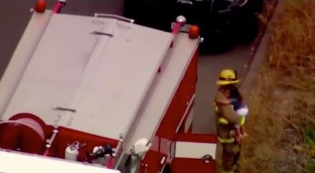 A firefighter has been hailed a hero for picking up a little girl and hugging her to distract her from a car crash. Photo: NBC