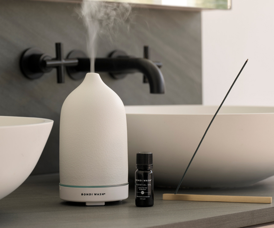 An image of the white Bondi Wash aromatherapy diffuser next to a sink in a bathroom.