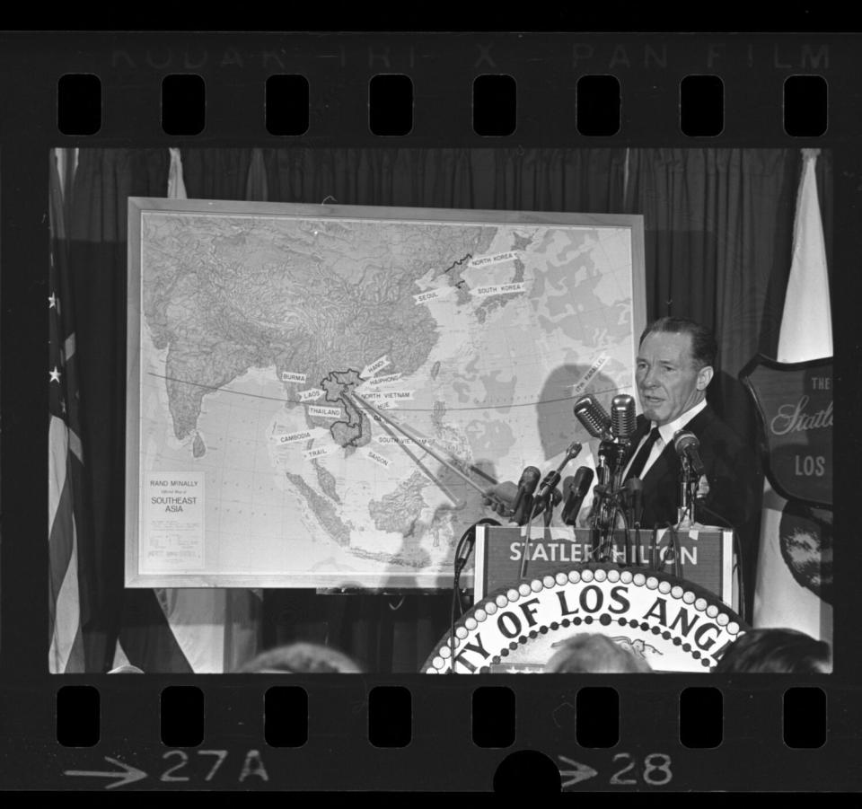 A man with a pointer points at Southeast Asia on a map during a news conference