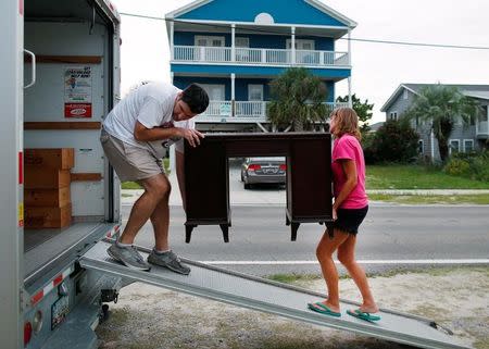 Dean Legge (L) helps his sister-law Josey Vereen (R) remove furniture from the lower level of her beachfront home along Waccamaw Drive in anticipation of Hurricane Matthew in Garden City Beach, South Carolina, U.S. October 4, 2016. REUTERS/Randall Hill