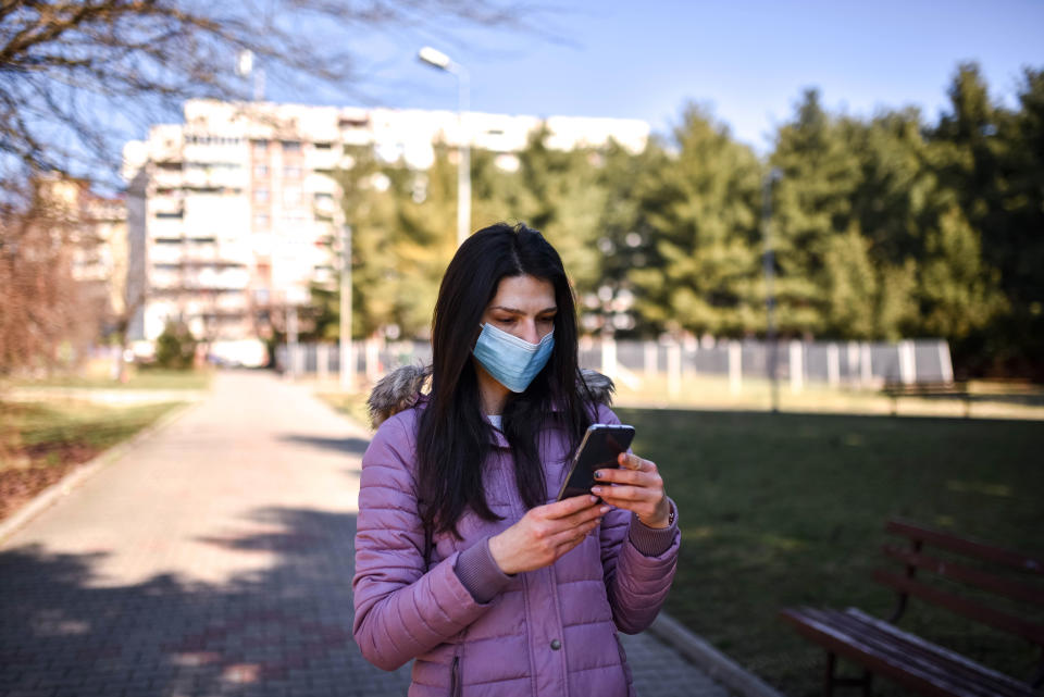 a woman with a face mask that uses a cellphone