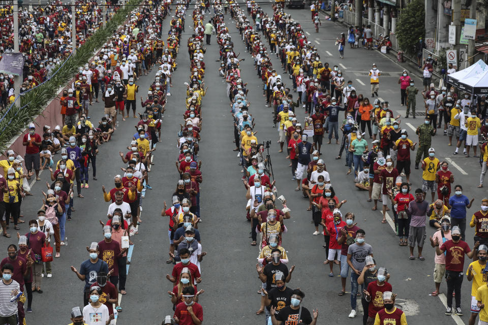 Thousands of Catholic devotees line up as they celebrate the feast day of the Black Nazarene at the Minor Basilica of the Black Nazarene in downtown Manila, Philippines, Saturday Jan. 9, 2021. Hundreds of church workers and police were spread around the area to maintain order and enforce strict social distancing health protocols. The annual procession has been cancelled amid the threat of the ongoing COVID-19 pandemic in one of Asia's biggest religious events. (AP Photo/Gerard Carreon)