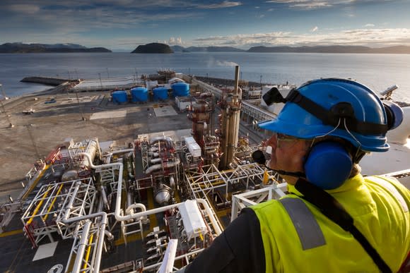 A worker overlooks an industrial oil and gas complex.