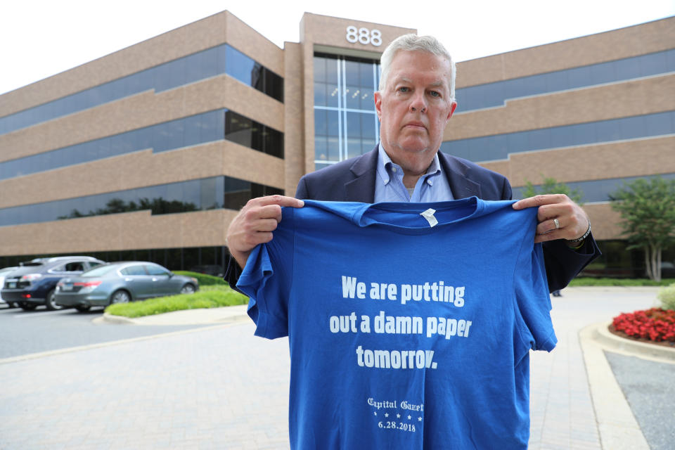 Ray Feldmann, who lives blocks away from the Capital Gazette's former office where five people were killed in a 2018 mass shooting, stands in front of the building Monday, June 21, 2021, in Annapolis, Md. He holds a shirt with a quote from Chase Cook, a staffer at the newspaper who is no longer there after taking a recent buyout, who made the comment in a tweet after the attack. Opening statements in the second phase of the gunman's trial to determine whether he is criminally responsible due to mental illness are scheduled for Tuesday, June 29. Jarrod Ramos already has pleaded guilty to all 23 counts against him. (AP Photo/Brian Witte)